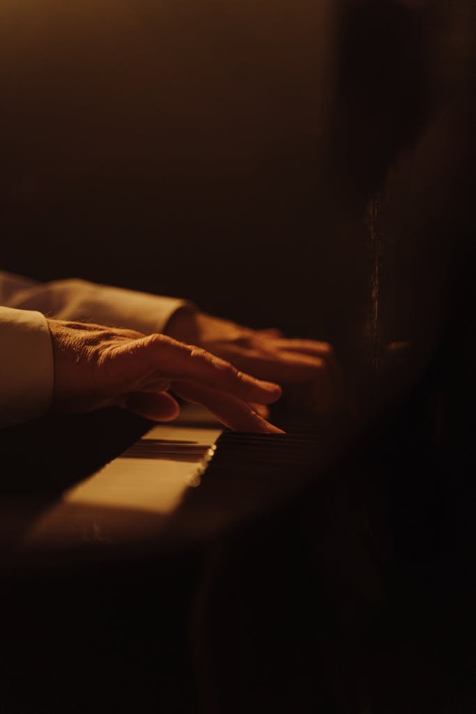 A dramatic close-up of hands playing a piano with warm lighting, capturing musical expression.