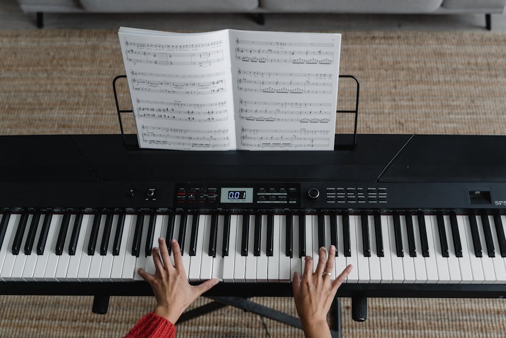Top view of hands playing piano with sheet music on display, perfect for music learning themes.